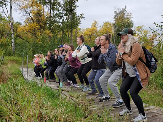 Women in yoga pose along trail boardwalk