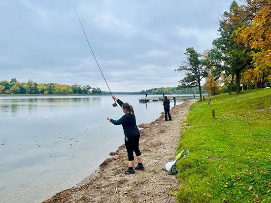 Fly fishing along shore surrounded by colorful fall leaves